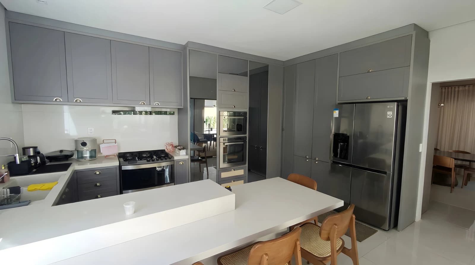 Cozinha gourmet com armários cinza Alpina Satin, portas provençais, bancada Silestone Branco Diamante e vidro Rflecta Cristal.