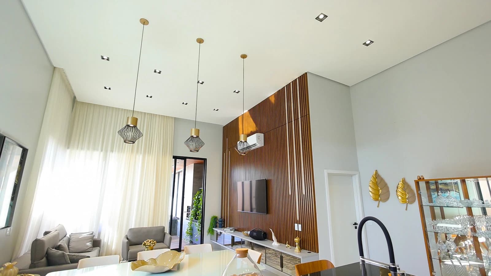 Home theater com painel ripado em Louro Freijó, base Branco Diamante, LED embutido e espelho bronze.