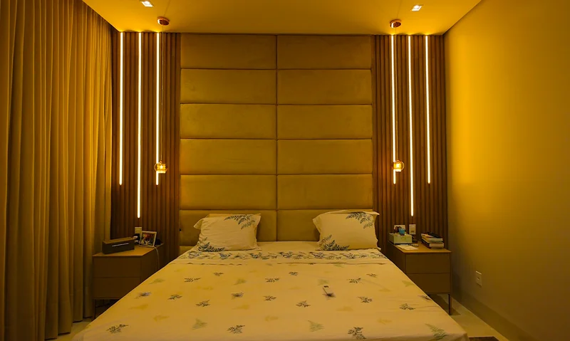 Quarto de casal piso-teto com cabeceira estofada até o teto, moldura em MDF freijó e arauco cacau e LED embutido.