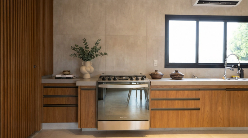 Cozinha de fazenda com armários em MDF Louro freijó, Portas Roma em alumínio bronze e bancada clara sob luz natural.