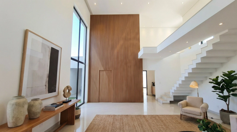 Living com painel ripado piso-teto em MDF Louro Freijó, pé-direito alto, janelas amplas e escada branca.