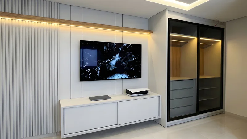 Home theater com painel e rack em MDF Aurora, roupeiro com vidro Dark Translucid e iluminação difusa
