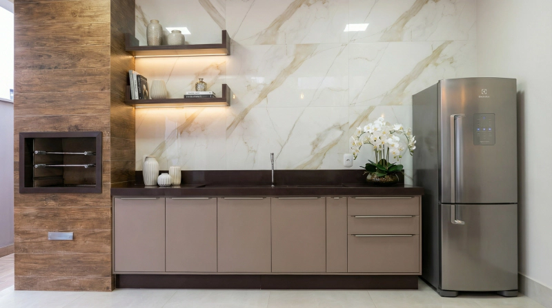 Bancada com pedra Café, MDF Chocolat Light e portas Versatile champagne em churrasqueira gourmet com iluminação suave.