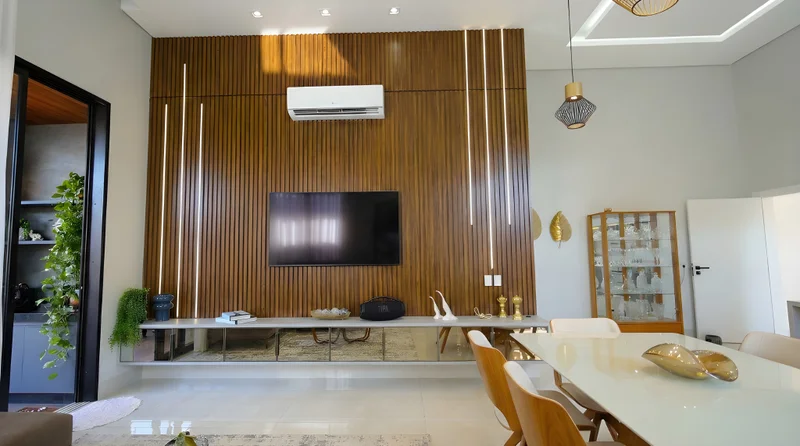 Home theater com painel ripado em Louro Freijó, base Branco Diamante, LED embutido e espelho bronze.