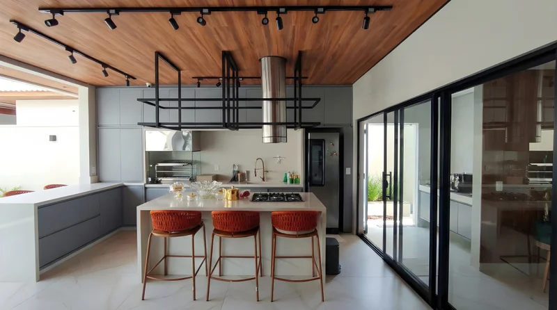Varanda gourmet com ilha em pedra Bege Ártico, armários em MDF Gouthier Mesh e portas Roma com Alumínio Bronze.