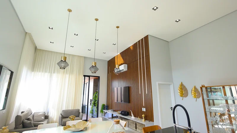 Home theater com painel ripado em Louro Freijó, base Branco Diamante, LED embutido e espelho bronze.